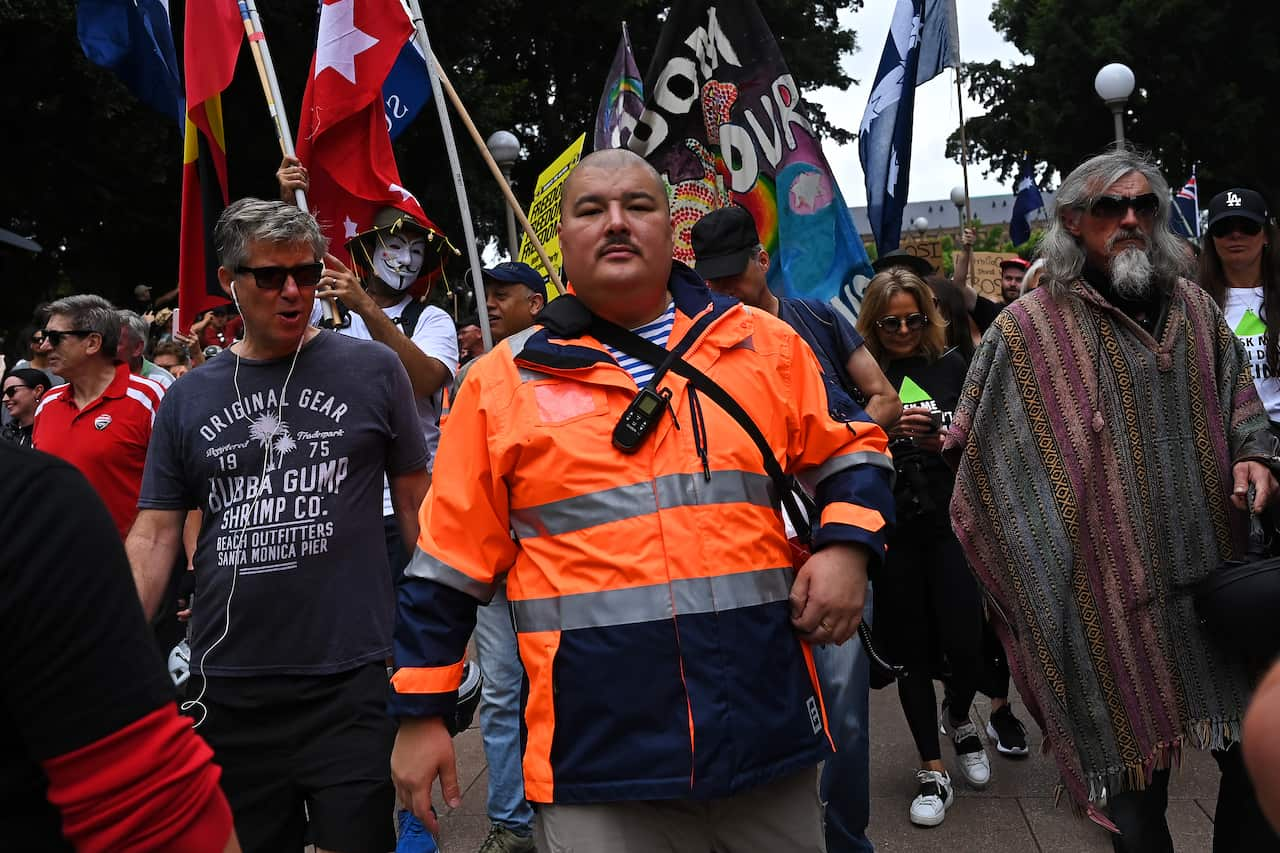 A man in a high-vis jacket in a crowd. 