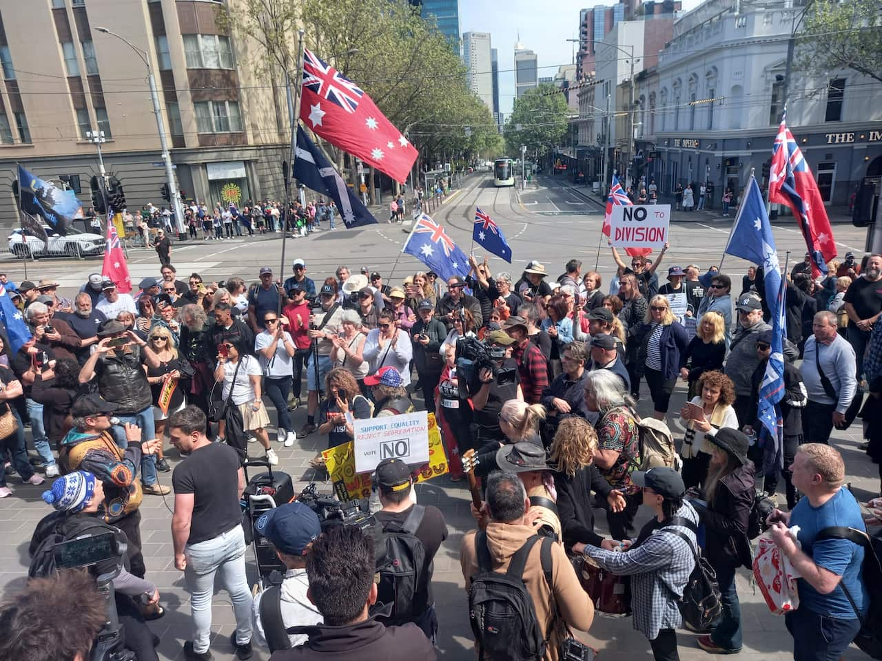 A large crowd of people holding placards and Australian flags