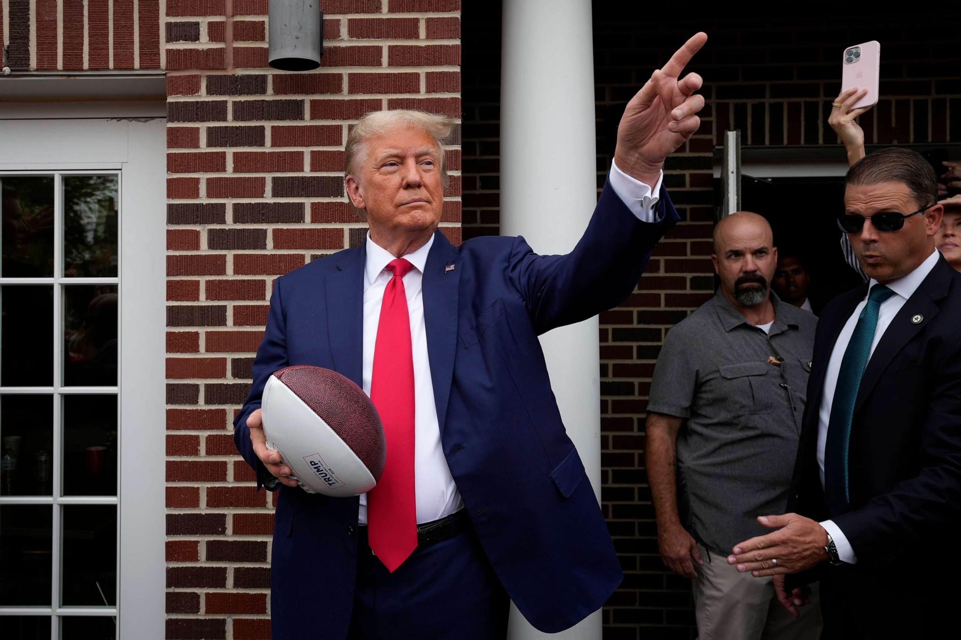 PHOTO: Former President Donald Trump holds a football before throwing it to the crowd during a visit to the Alpha Gamma Rho, agricultural fraternity, at Iowa State University before an NCAA college football game, Sept. 9, 2023, in Ames, Iowa.