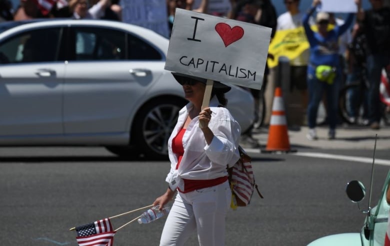 A demonstrator holds a sign reading "I Love Capitalism" while protesting against the state's stay-at-home order amid the coronavirus pandemic, on May 1, 2020 in California. 