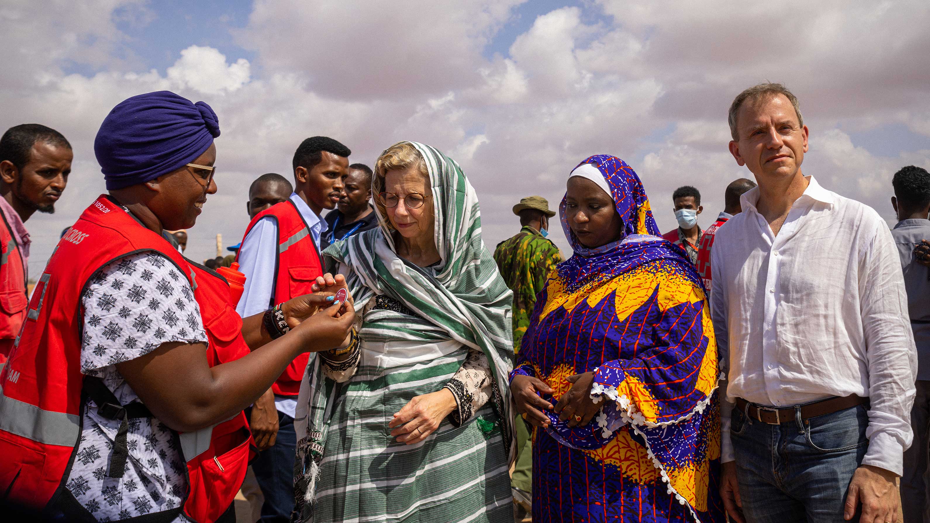 Red Cross Chair hands out a pin to UNEP Executive Director. A woman and Stephen stand next to them.