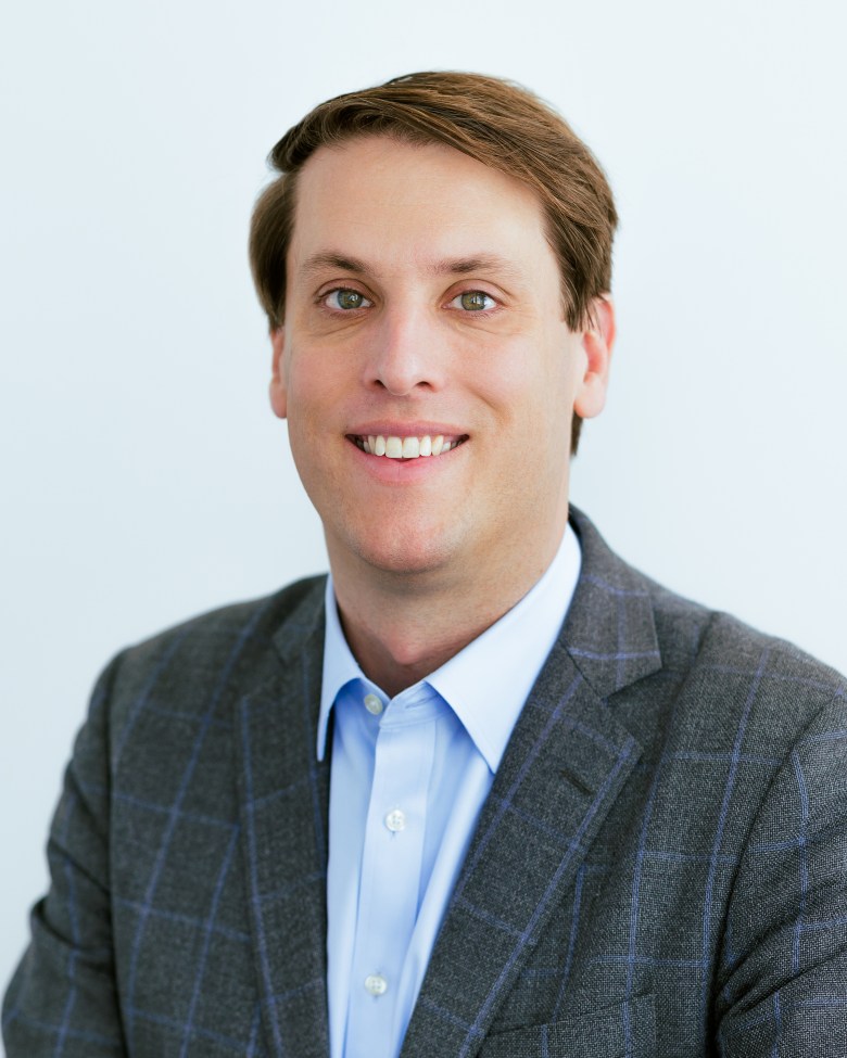 A man in a suit smiling for the camera.