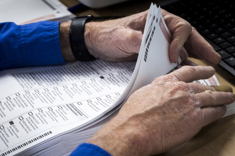 A worker organizes a stack of mail-in ballots.