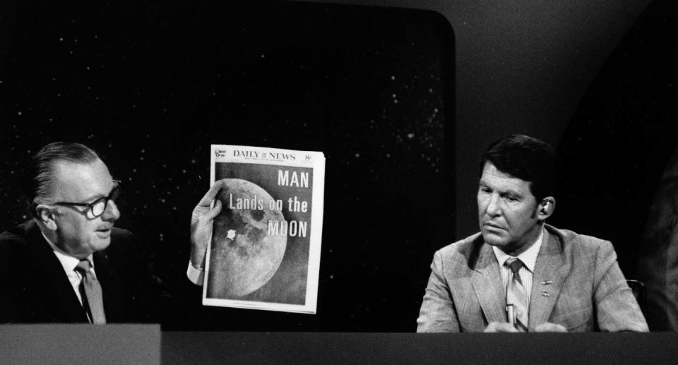 Newsreader Walter Cronkite holding up a newspaper announcing the moon landing