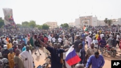 FILE - Nigeriens, some holding Russian flags, participate in a march called by supporters of coup leader Gen. Abdourahmane Tchiani in Niamey, Niger, on July 30, 2023. (AP Photo/Sam Mednick)