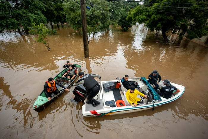 PORTO ALEGRE, BRAZIL - MAY 11: A speedboat tows a boat transporting people who were rescued from the floods on May 11, 2024 in Porto Alegre, Brazil. According to the Meteorological Service, a cold front is causing new heavy rains that can exceed the 150 mm causing more damage to the city and increase in the water levels. (Photo by Jefferson Bernardes/Getty Images)