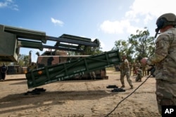 Membesr of the U.S. Army prepare a crane for loading the Army Tactical Missile System (ATACMS) on to the High Mobility Artillery Rocket System (HIMARS) in Queensland, Australia on July 26, 2023. (Sgt 1st Class Andrew Dickson/U.S. Army/ via AP)