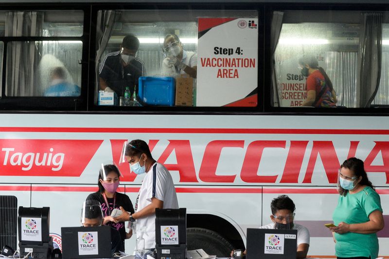 © Reuters. FILE PHOTO: Health workers encode information and prepare vaccines against the coronavirus (COVID-19) at a mobile vaccination site in Taguig, Metro Manila, Philippines, May 21, 2021. REUTERS/Lisa Marie David/File Photo