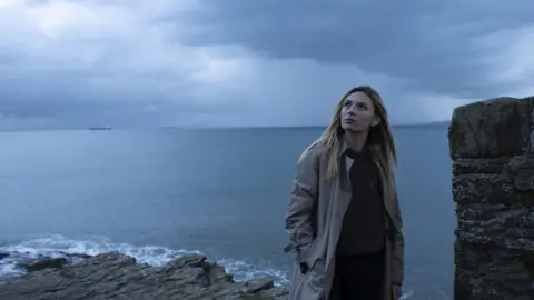 BBC/Twenty Twenty Productions Ltd/Rory Jackson Sian Eleri standing on a cliff top looking up at the sky