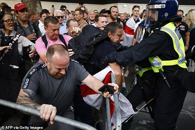 Protesters try to break through a barrier as riot police wearing helmets try to control the violence in London on Wednesday