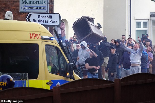 Protesters cheer as they launch bins at riot police vans amid ugly scenes on Tuesday in Southport