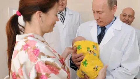 AFP Vladimir Putin holds a baby during a tour of a hospital