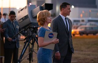 A woman and man stand next to '60s-era TV camera