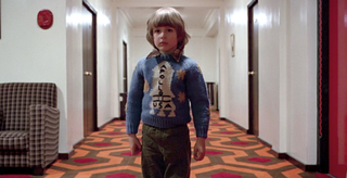 A young boy stands in a hotel hallway wearing an Apollo 11 sweater