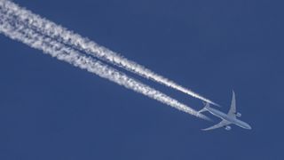 An aircraft releases trails of condensation behind it