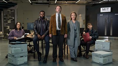 Izuka Hoyle, Dipo Ola, David Mitchell, Dorothy Atkinson, Gerran Howell looking seriously at the camera in a room with boxes filled with paperwork