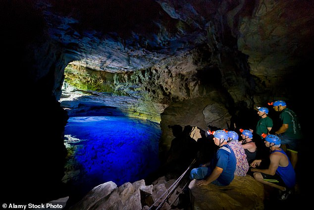 Above, tourists admire the 'Poco Encantado' (aka 'the Enchanted Well') a sunken, subterranean pool and tourist destination at Chapada Diamantina National Park