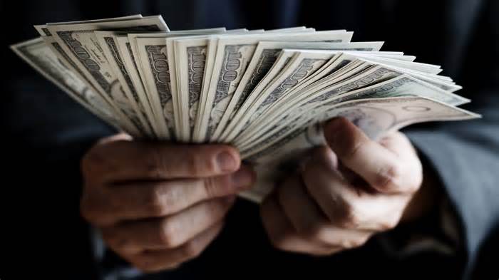 rich wealthy man hands holding cash 100 dollar bills_iStock-938914620