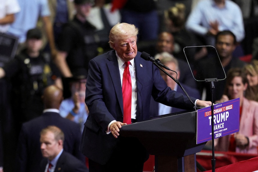 Donald Trump stands at a podium at a campaign rally