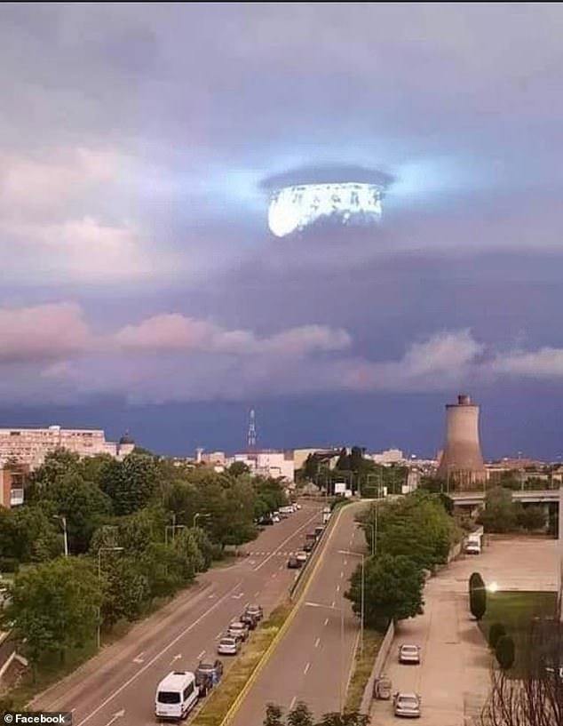 The higher resolution image of this apparent 'mothership,' which looks at first glance to be piercing clouds with its beatific shafts of light, appears more likely to have originated as the reflection of an indoor chandelier lamp reflected in window glass