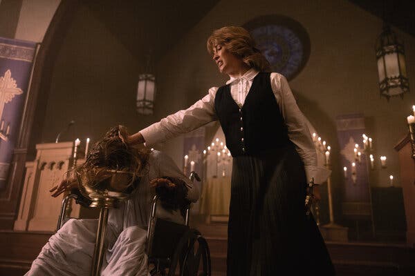 A photograph shows a woman in a dimly lit church dunking someone’s face into a bowl of water.