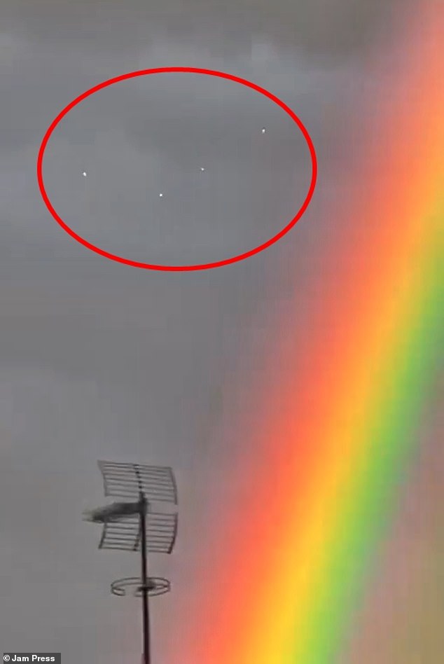 Footage shows the unidentified lights which local conspiracy theorists believe to be 'UFOs' darting through the sky over a residential area in Barcelona among the rare twin rainbows