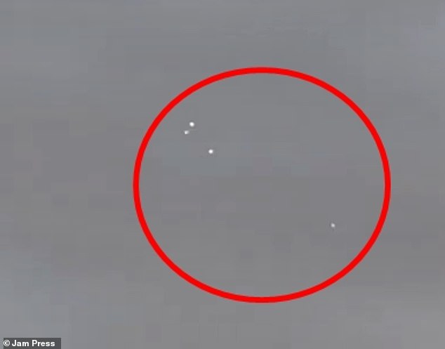 As the cameraman zoomed in to get a closer look at these white specs of light, the video shows them whizzing through the clouds