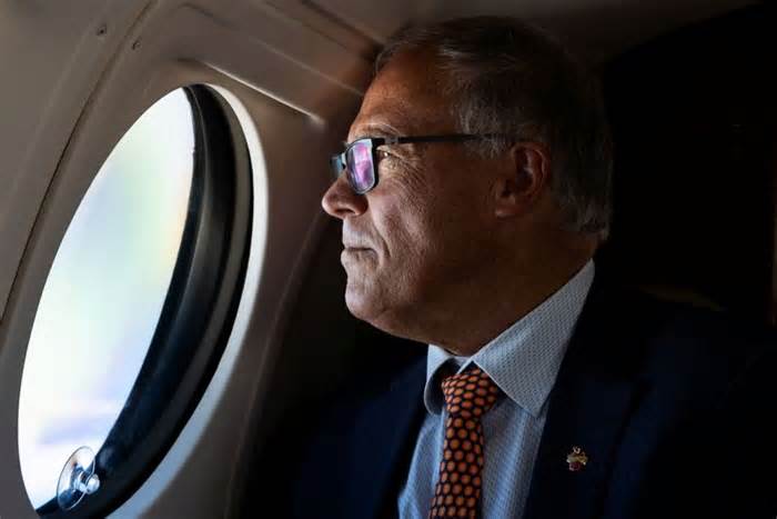 Washington Governor Jay Inslee looks out the window of a Washington State Patrol plane while traveling across the state