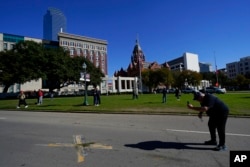 FILE - A person uses a cellphone to capture images of an X on Elm Street at Dealey Plaza, one of two spots marked where President John F. Kennedy was shot, as people gather on the 60th anniversary of his assassination, Nov. 22, 2023, in Dallas.