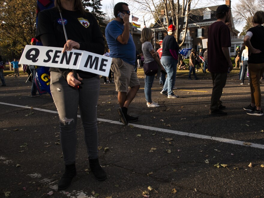 A woman holds a sign referencing the QAnon conspiracy on Nov. 7, 2020, in St. Paul, Minn. QAnon emerged online in 2017 and claims that Trump is involved in a secret battle against evil members of the alleged deep state, or in other tellings, a powerful cabal of government and Hollywood elites engaged in satanic child abuse.