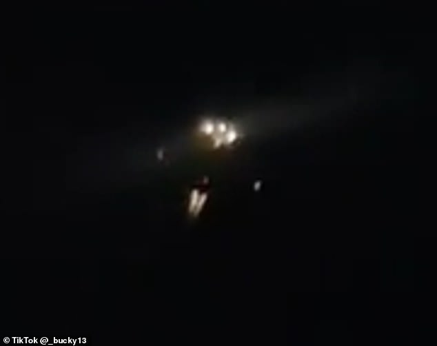 One of the UFO drones, whose engines can be heard roaring from the ground, appeared to have a cluster of white lights on its underbelly with red lights blinking at its wingtips and tail (above)