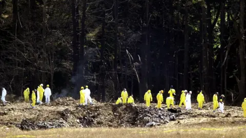 Reuters Investigators comb the debris field for the flight data recorders from United Airlines Flight 93 near Shanksville, Pennsylvania, September 12, 2001