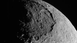 a close-up of a crater-pocked moon as taken by a spacecraft orbiting Saturn