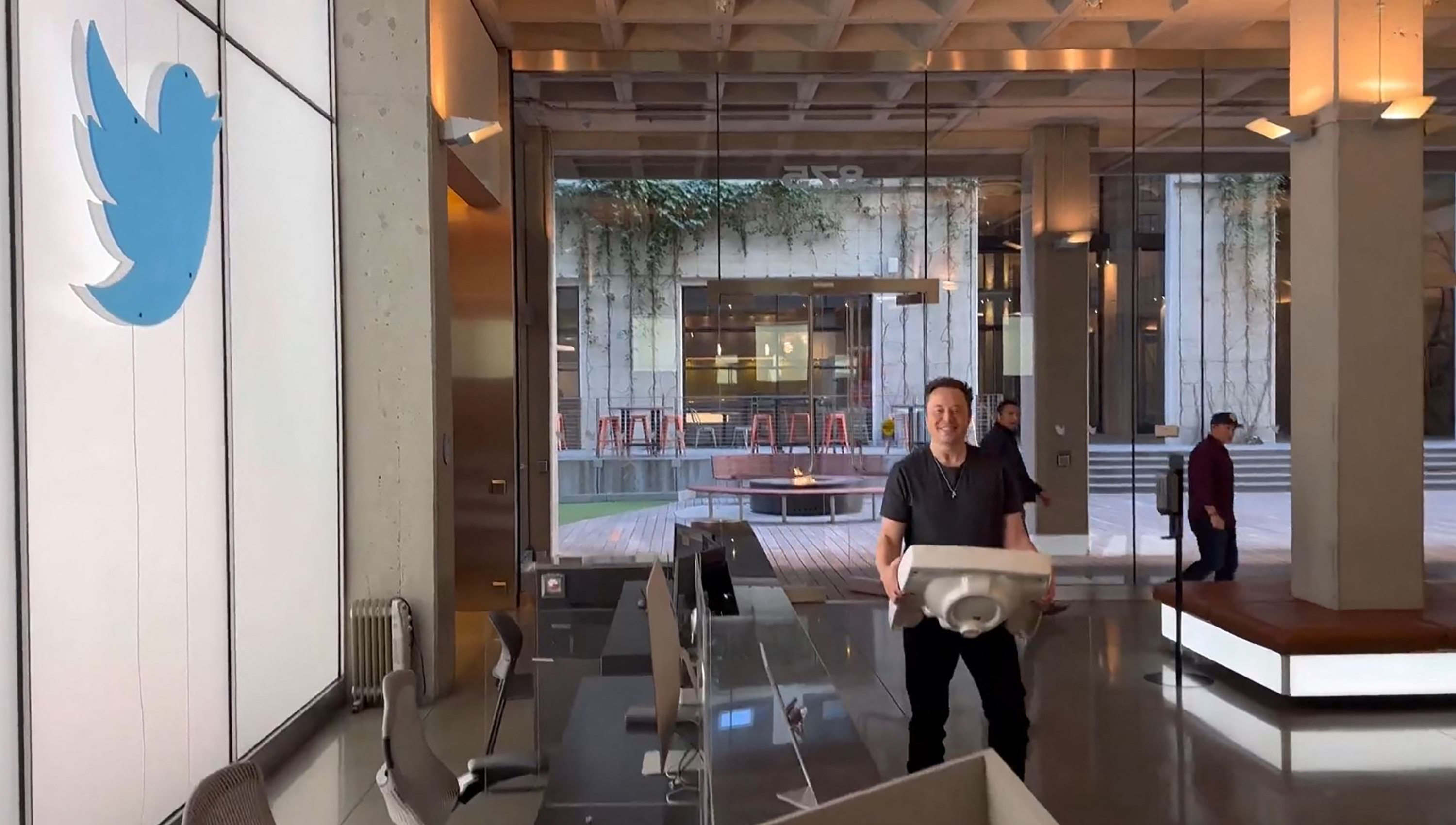 Elon Musk carries a bathroom sink into Twitter headquarters.