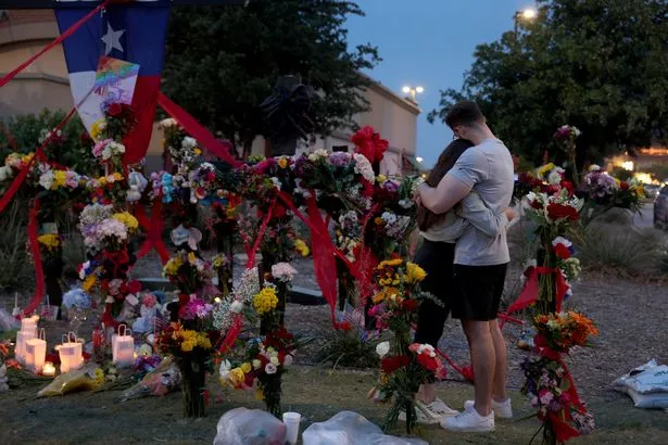 People hug as they visit the memorial next to the Allen Premium Outlets on May 7, 2023 in Allen, Texas. The memorial is for the victims of the May 6th mass shooting in the Allen Premium Outlets mall.