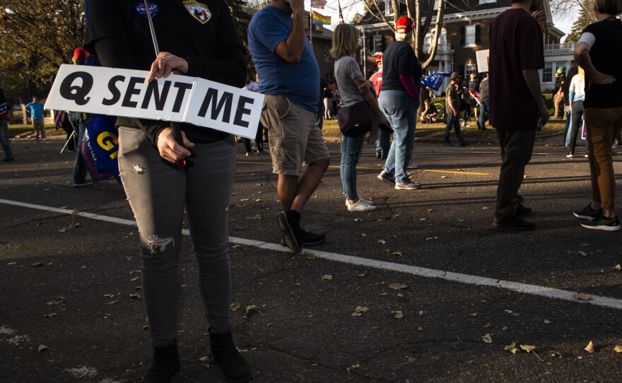 A woman holds a sign referencing the QAnon conspiracy on Nov. 7, 2020, in St. Paul, Minn. QAnon emerged online in 2017 and claims that Trump is involved in a secret battle against evil members of the alleged deep state, or in other tellings, a powerful cabal of government and Hollywood elites engaged in satanic child abuse.