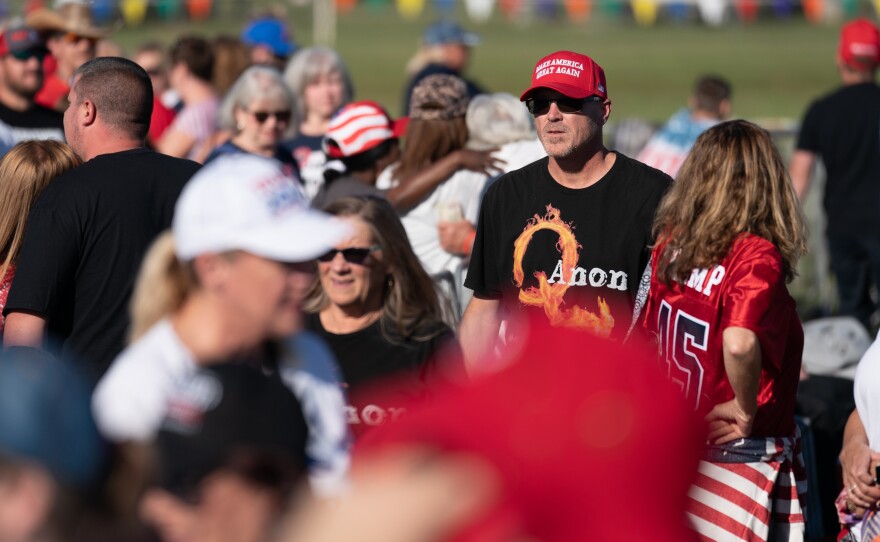 A man wearing a QAnon t-shirt walks through the crowd at a Trump rally on Sept. 25, 2021 in Perry, Ga. The nonprofit PRRI, which conducts polls on religion, found that 19% of Americans believe in the core theories associated with QAnon, up from 14% in 2021. The poll found the number rose to 32% among Republicans who support Trump.