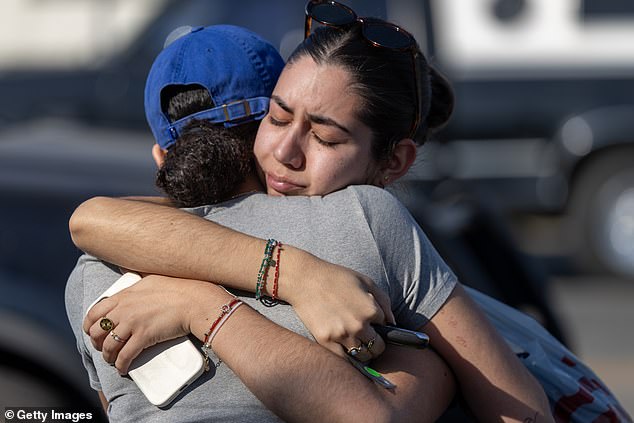 People hug in a neighborhood where many homes were destroyed by the Eaton Fire on January 11, 2025 in Altadena, California